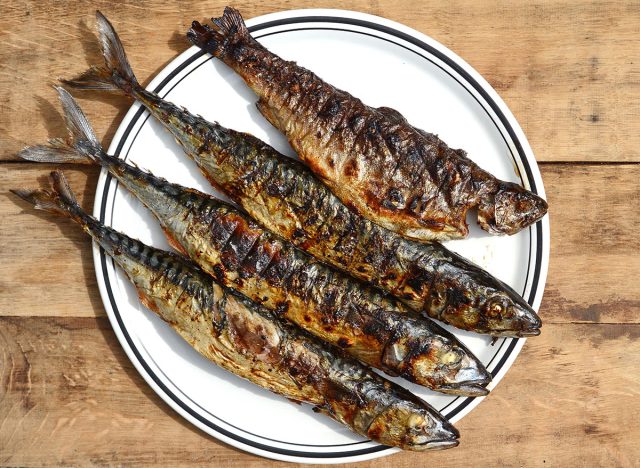 Grilled Mackerel fish on a white plate. Fatty, oily fish is an excellent and healthy source of DHA and EPA, which are two key types of omega-3 acid.