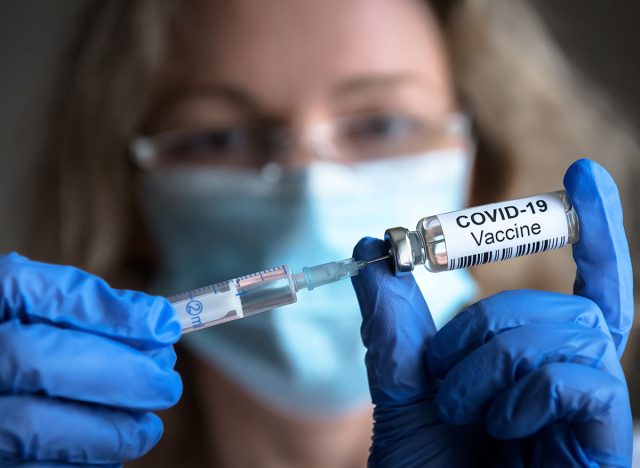 COVID-19 vaccine in researcher hands, female doctor's holds syringe and bottle with vaccine for coronavirus cure. Concept of corona virus treatment, injection, shot and clinical trial during pandemic