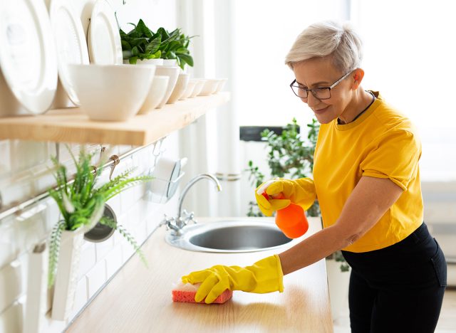 beautiful adult woman with glasses in a yellow t-shirt does house cleaning