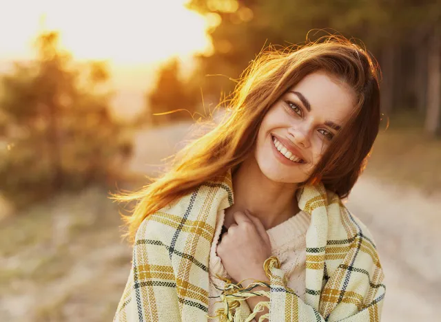 Happy woman with bread on her shoulders laughs front view and sunset in the background