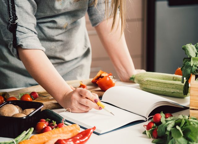 Unrecognizable woman is looking for recipes in cookbook.