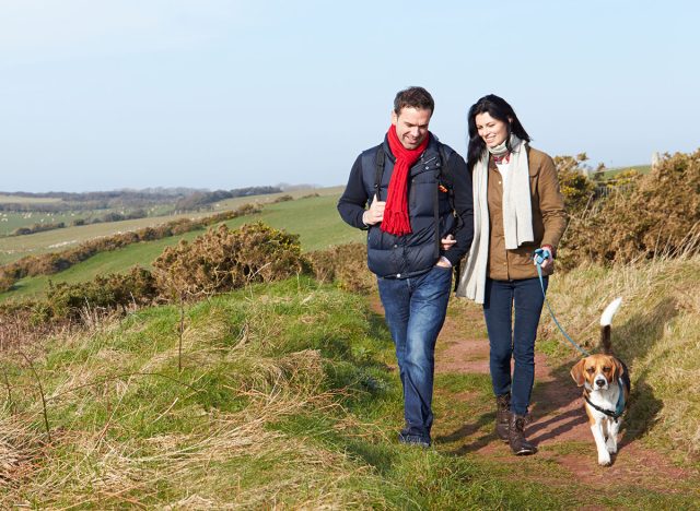 Couple With Dog Walking Along Coastal Path