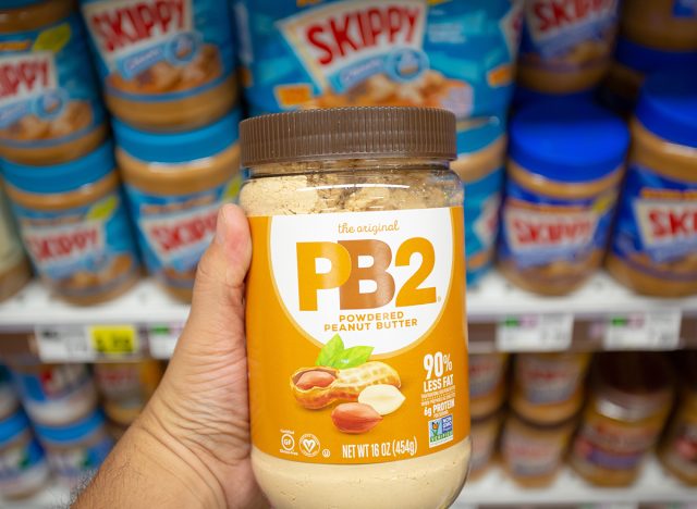 Los Angeles, California, United States - 10-25-2021: A view of a hand holding a jar of PB2 powdered peanut butter, on display at a local grocery store.