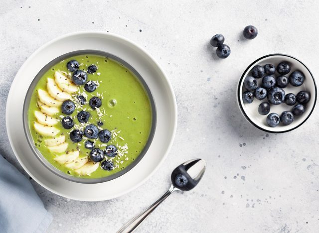 matcha green tea smoothie bowl with banana, almond milk, blueberries, chia seeds and coconut. Healthy vegan food concept. Gray background. top view