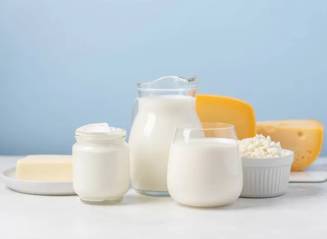 Milk, yogurt, cottage cheese, cheese, butter on light table and blue background. Side view of variety of dairy products