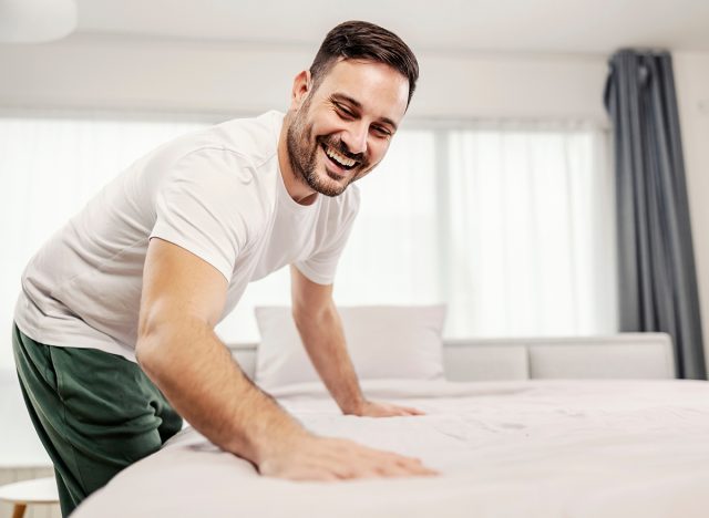 A tidy morning man making his bed in the morning at his cozy home.