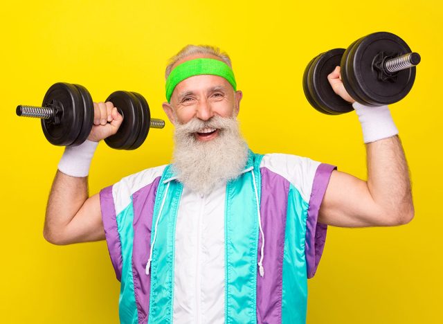 Photo of excited cheerful granddad toothy smile hands hold lift dumbbells isolated on yellow color background