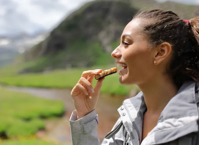 Profile of a hiker eating a cereal bar in the mountain