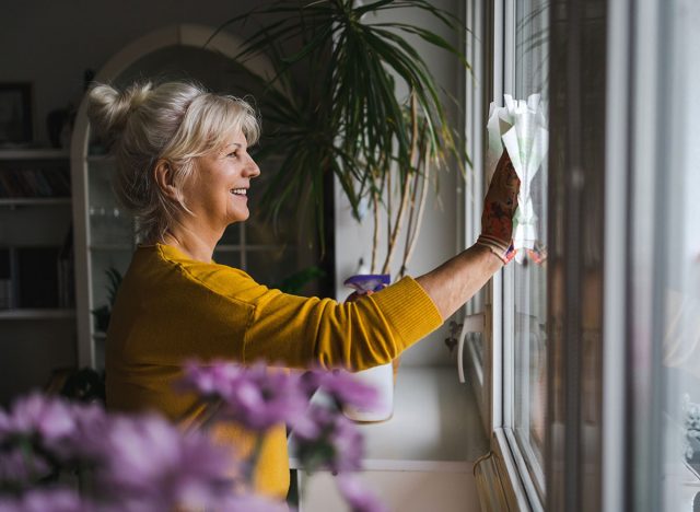 Mature woman cleaning windows in her home