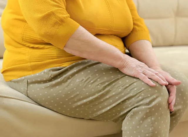 Senior fat woman holding the knee with pain.