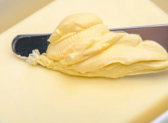 Butter and margarine in a butter dish and a knife on which the greasy spread is collected after touching the cube