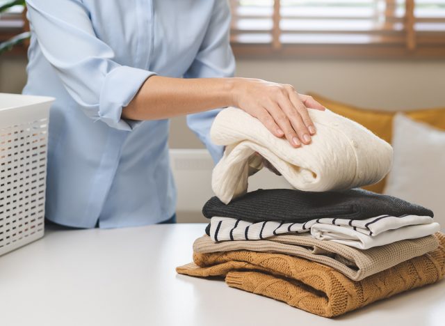 Feel softness, asian young woman, female hand holding pile clothing from table, stack folding clean clothes after washing, laundry and dry. Household working at home. Laundry and maid concept.