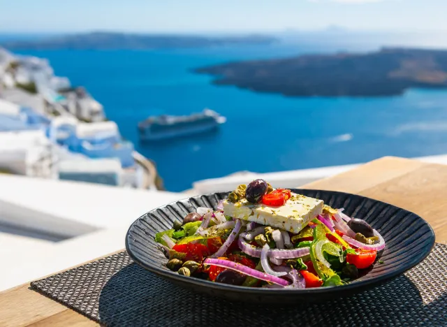 Greek salad with beautiful sea view in Santorini island, Greece. National greek cuisine concept. Travel and vacation