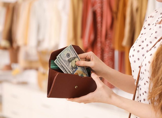 Young woman with wallet and money in boutique, closeup