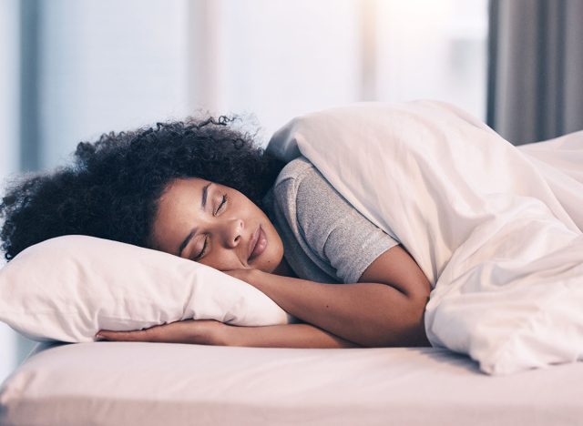 Sleeping, woman and bed with nap at home in morning with rest feeling calm with peace. House, bedroom and tired female person relax and comfortable on a pillow with blanket dreaming over the weekend