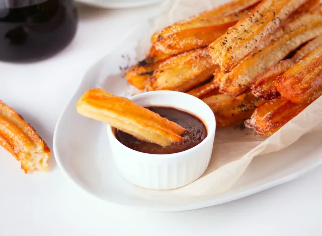 Traditional spanish treat street fast food churros on a plate with hot chocolate sauce