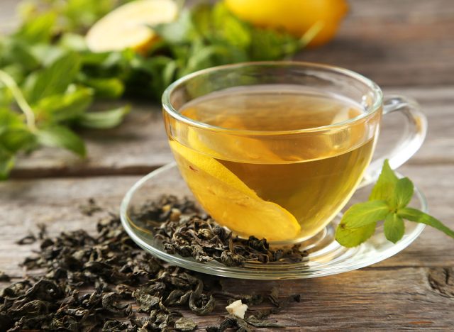 Cup with green tea on grey wooden background