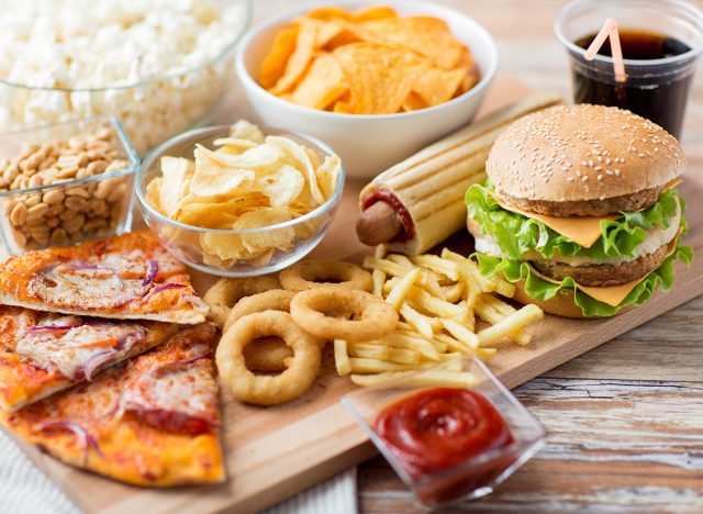 fast food and unhealthy eating concept - close up of fast food snacks and cola drink on wooden table