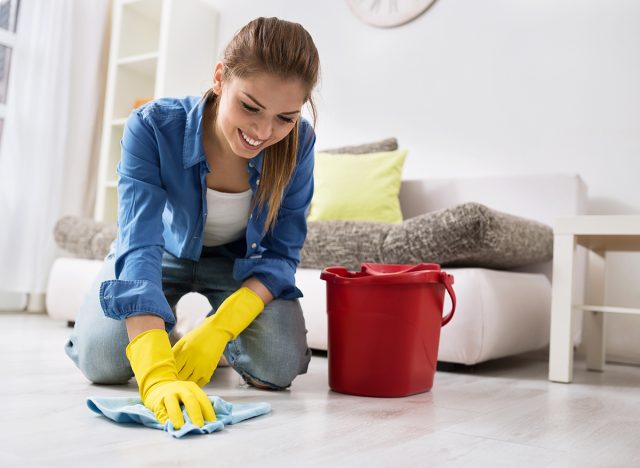 Smiling girl wash the floor with rag and detergent