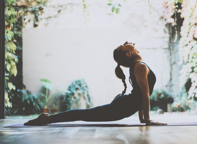 Portrait of gorgeous young woman practicing yoga indoor. Beautiful girl practice cobra asana in class.Calmness and relax, female happiness.Horizontal, blurred background