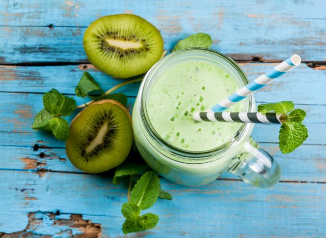 Refreshing Summer green smoothie or milkshake with mint, yogurt and kiwi. in mason jar, on blue wooden table, copy space, top view