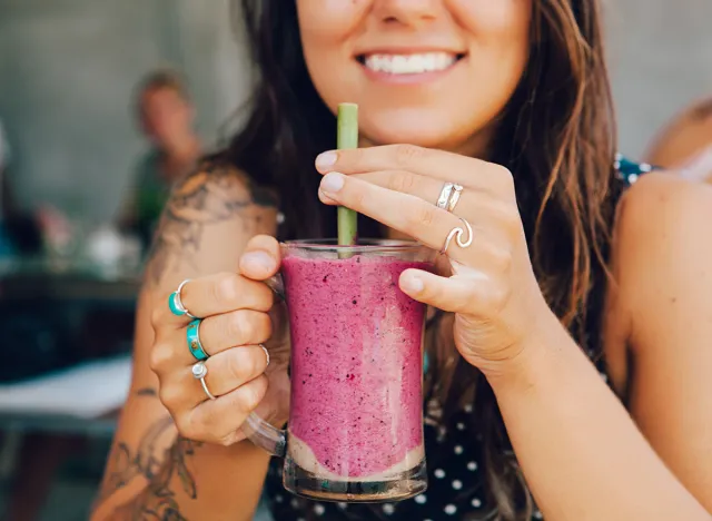 Young girl having a good morning healthy breakfast smoothie drink made of super foods, fruits, nuts, berries