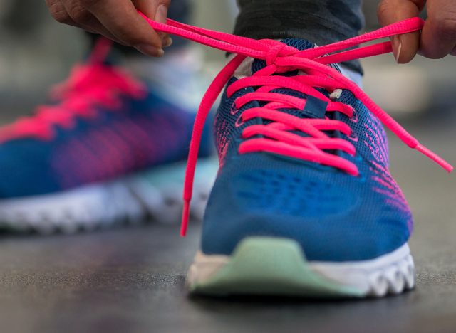 Running shoes - woman tying shoe laces. Closeup of fitness woman getting ready for engage in the gym