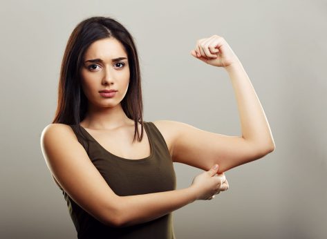 Young woman pinching arm fat flabby skin