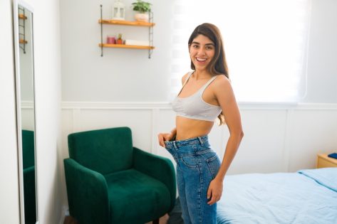 Portrait of an attractive hispanic woman wearing a size too big jeans.