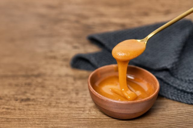 Manuka honey dipper dipping in raw organic liquid from Manuka flowers in New Zealand