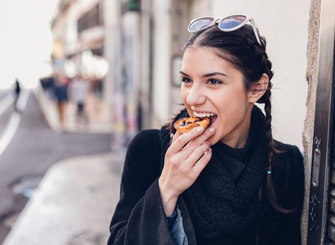 European tourist woman trying out local food.Eating traditional Portuguese egg custard tart pastry dessert pastel de Nata.
