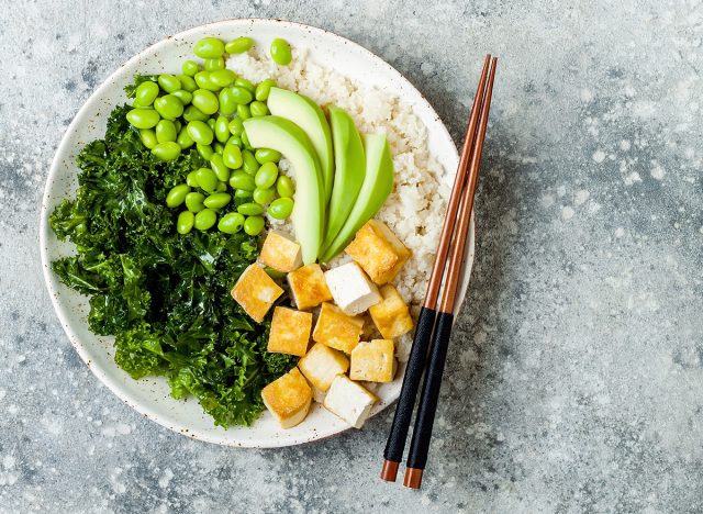 Cauliflower rice Buddha bowl with massaged kale, tofu, avocado and edamame beans. Vegan poke bowl