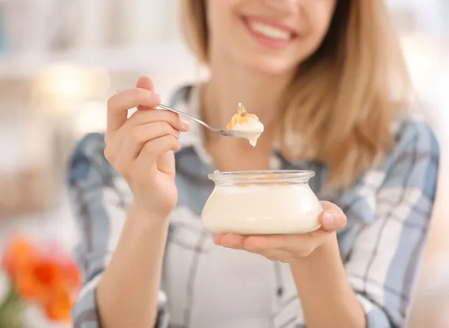 Young woman eating tasty yogurt, closeup