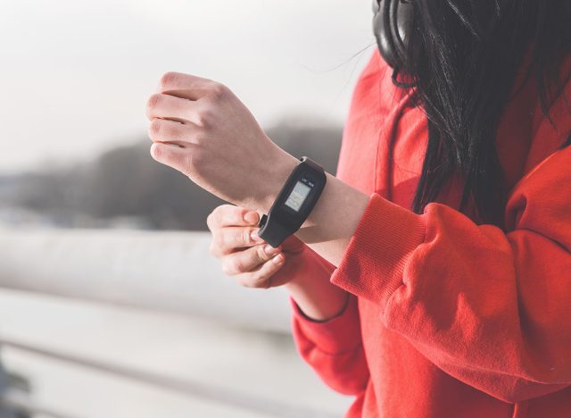 Closeup cropped photo of female runner putting a pedometer on her wrist, Sports equipment and gadgets concept