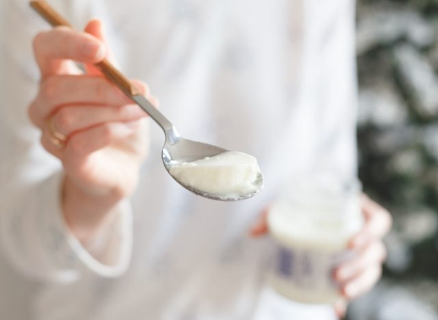 Spoon with thermostat yogurt in a girl's hand