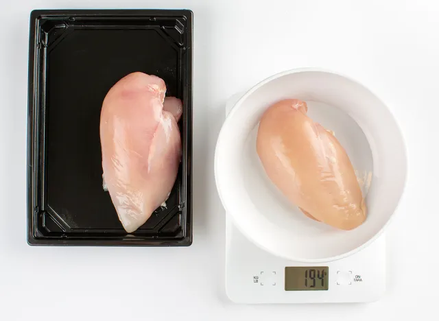 Raw chicken breast on tray on white background