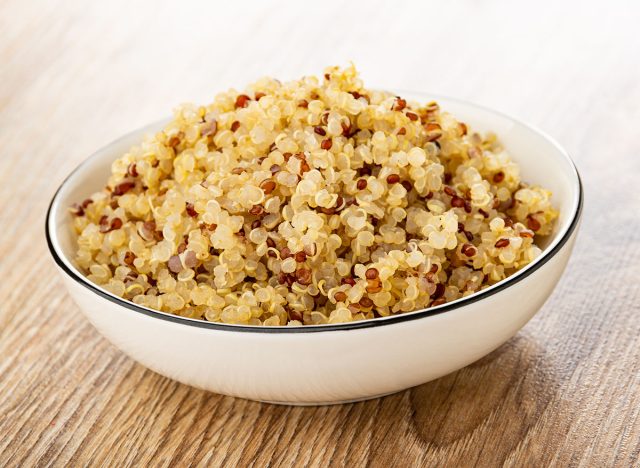 Boiled quinoa in white bowl on brown wooden table