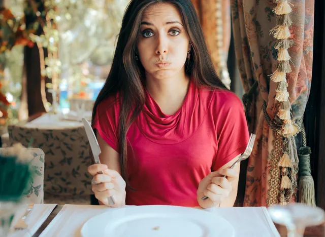 Stressed Woman Having a Pill Before the Meal in a Restaurant. Unhealthy dieting with extreme measures of being in a caloric deficit