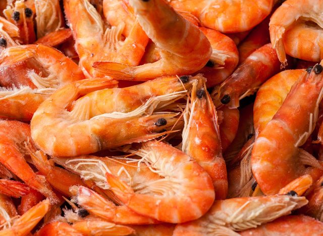 Frozen shrimp. Seafood on the counter. Fish market. Close-up shooting of seafood. Box with shrimp. Photo of shrimp in the supermarket. Wholesale of fish. Peeled shrimp.