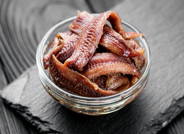 canned anchovy fillet on a black wooden rustic background.