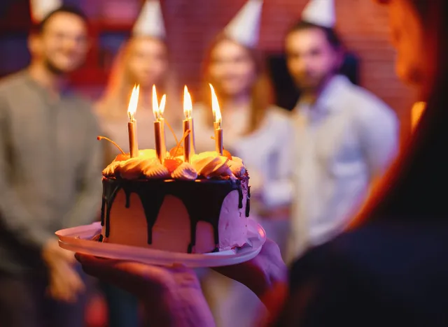 Cropped photo of a plate with birthday cake in woman's hands