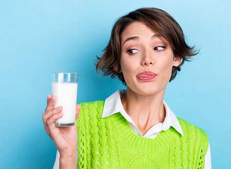 Photo of nice funny lady look hand hold fresh milk glass tongue lick lip isolated on blue color background