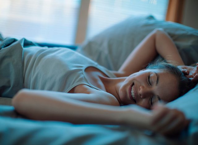 Young Caucasian woman sleeping in her bed and having happy dreams