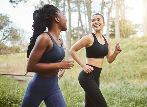 Happy woman, friends and running in forest for workout, training or outdoor cardio exercise together. Active female person, athlete or runners smile for sports run, sprint or race in nature fitness