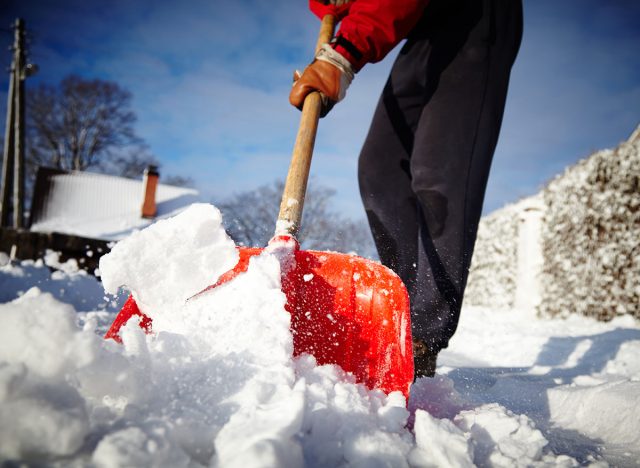 Man with snow shovel cleans sidewalks in winter. Winter time. Latvia. Europe.