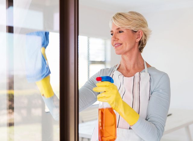 beautiful senior woman cleaning window glass