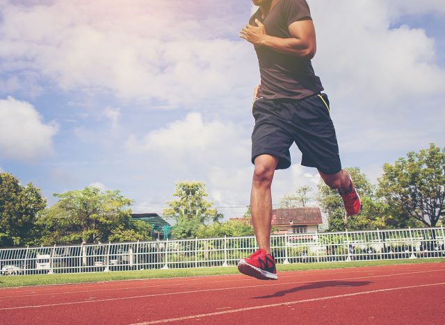 man running in the track. Fit male fitness runner jogging in stadium