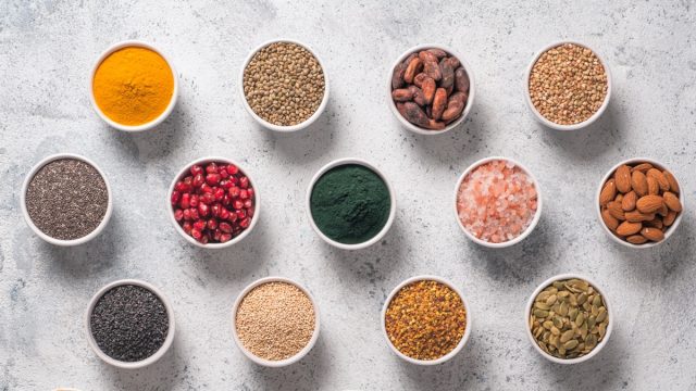 Various superfoods in smal bowl gray concrete background. Superfood as chia, spirulina, raw cocoa bean, goji, hemp, quinoa, bee pollen, black sesame, turmeric.