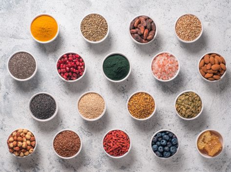 Various superfoods in smal bowl gray concrete background. Superfood as chia, spirulina, raw cocoa bean, goji, hemp, quinoa, bee pollen, black sesame, turmeric.