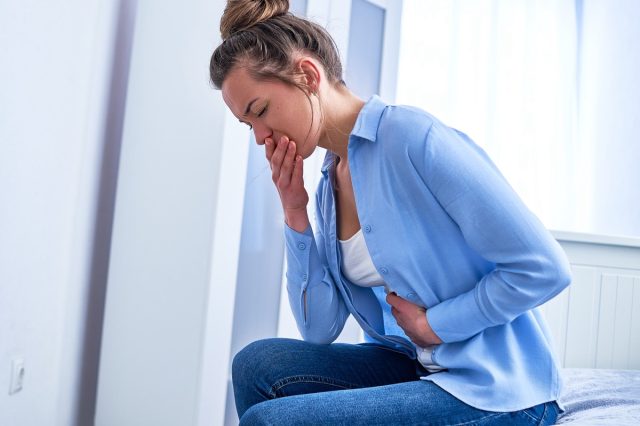 Woman suffers from nausea or stomach pain.